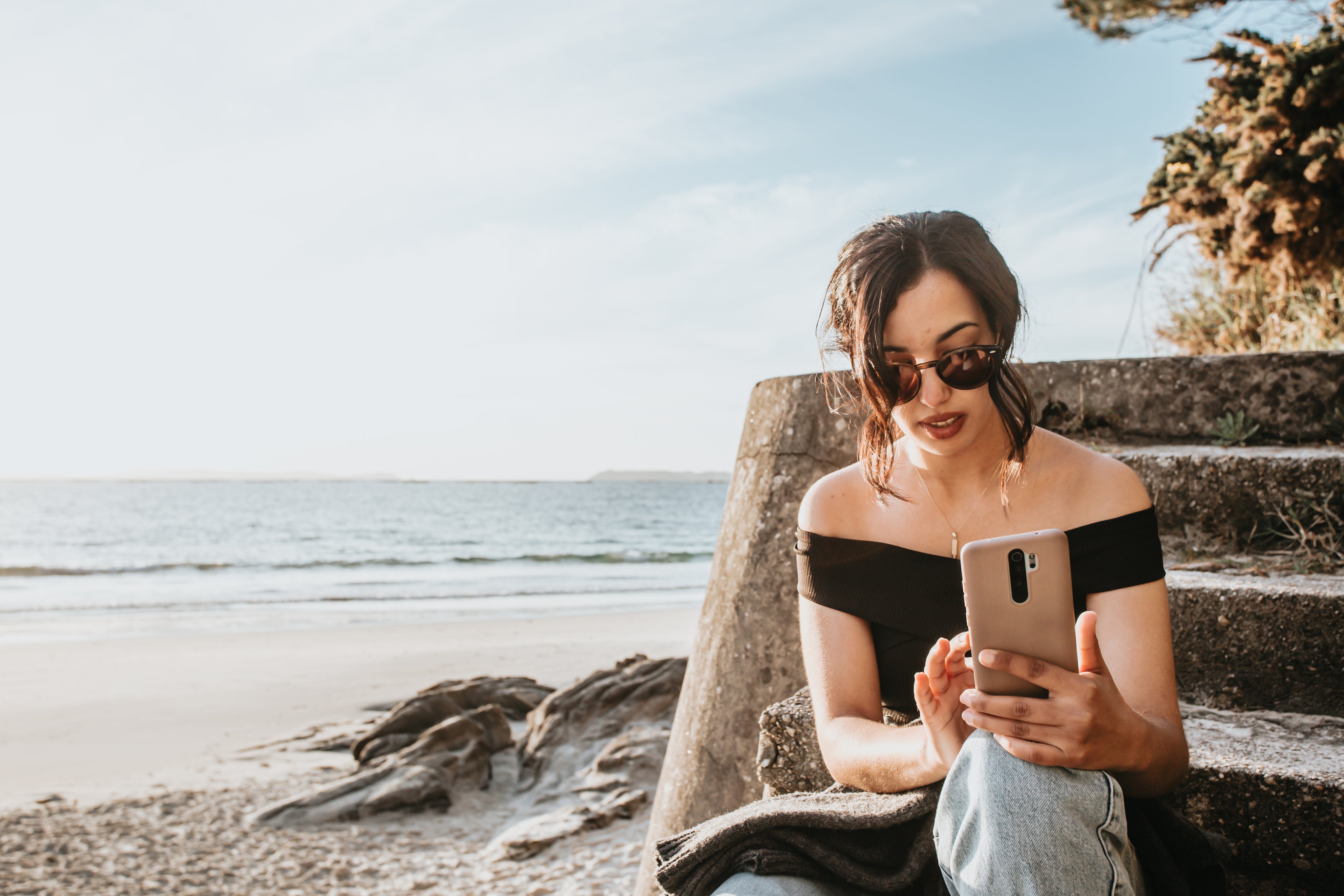 files/person-sits-on-steps-by-a-beach-looking-at-their-phone.jpg